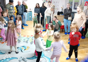 Dzieci tańczą na dywanie do muzyki.