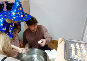 Dziewczynka z pomocą nauczycielki trzyma klucz nad miską z wodą, a jej tata wlewa przez dziurkę wosk.