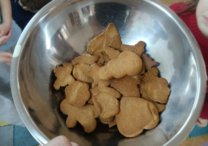 Pani prezentuje wykonane przez dzieci pierniczki w misce.