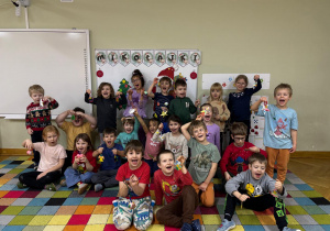 Cała grupa przedszkolaków pozuje do wspólnego zdjęcia z własnoręcznie wykonanymi ozdobami choinkowymi na zajęciach z mamą koleżanki w ramach projektu "Bohater Tygodnia".