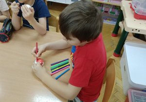 Chłopcy siedzą przy stolikach i dekorują markerami styropianowe dekoracje świąteczne wg. własnego pomysłu.