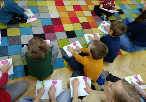 Dzieci z rodzicami wskazują poszczególne obrazki na kartce wg. instrukcji nauczycielki.