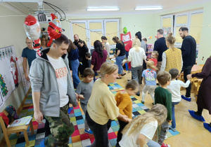 Dzieci wspólnie z rodzicami chodzą w koło po sali inscenizując opowieść ruchową gestami.