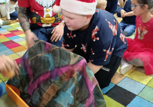 Chłopiec z zamkniętymi oczami wspólnie z tatą losuje słoiczek z wybranym zapachem i stara się go rozpoznać za pomocą węchu.