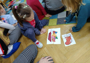 Dziewczynka układa wylosowane przez siebie puzzle na podłodze.