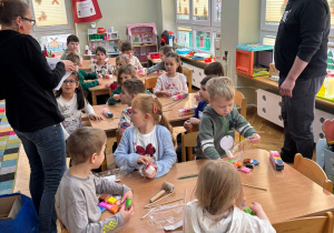 Dzieci siedzą przy stolikach i lepią wybrane przez siebie kształty z piankoliny przyniesionej przez kolegę w ramach projektu Bohater Tygodnia.