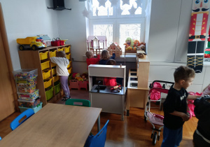 Dzieci bawią się w kąciku zabawek, wyciągając je z poszczególnych szuflad podczas wizyty na świetlicy szkolnej.
