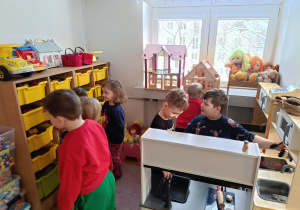 Dzieci bawią się w kąciku zabawek, wyciągając je z poszczególnych szuflad podczas wizyty na świetlicy szkolnej.