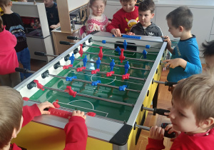 Chłopcy grają w piłkarzyki podczas wizyty na świetlicy szkolnej.