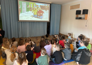 Dzieci oglądają bajkę na ekranie projekcyjnym.