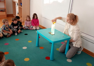 Dzieci obserwują eksperyment ze spadającym na dno wazonu kardamonem.