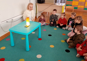 Dzieci obserwują eksperyment ze spadającym na dno wazonu kardamonem.