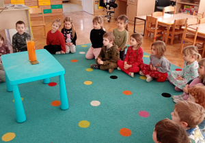 Dzieci obserwują eksperyment ze spadającym na dno wazonu kardamonem.