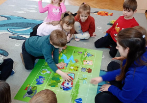 Chłopiec programuje robota stojącego na zielonej macie.