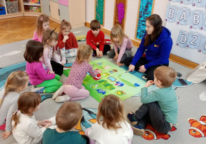 Dziewczynka programuje robota stojącego na zielonej macie.