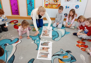 Przedszkolaki siedzą w kole, na środku układają proces wytwarzania pizzy.