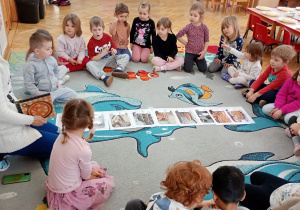 Przedszkolaki siedzą w kole i rozmawiają na temat procesu wytwarzania pizzy.