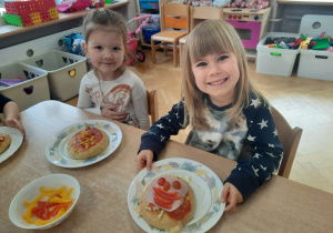 Dwie dziewczynki prezentują skomponowaną przez siebie pizze.
