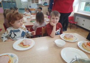 Dwóch chłopców prezentuje skomponowaną przez siebie pizze.