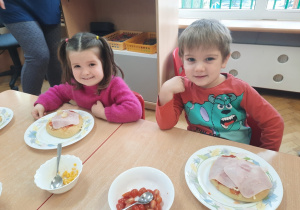 Dziewczynka i chłopiec prezentują skomponowaną przez siebie pizze.