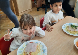 Dziewczynka i chłopiec prezentują skomponowaną przez siebie pizze.