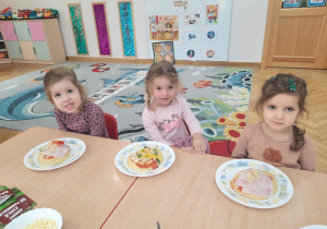 Trzy dziewczynki prezentują skomponowaną przez siebie pizze.