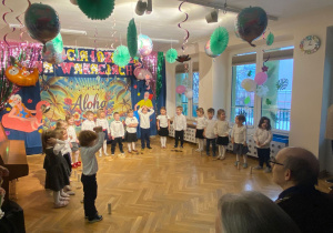 Dzieci stoją w półkolu i prezentują piosenkę dla Dziadków.