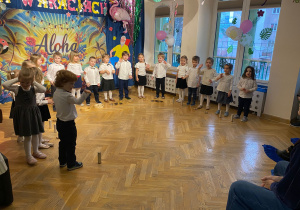 Przedszkolaki stoją w półkolu, przed nimi rozłożone są instrumenty.