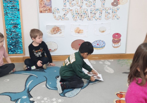 Chłopiec dokłada ilustrację największego pączka do istniejącego już ciągu obrazków.