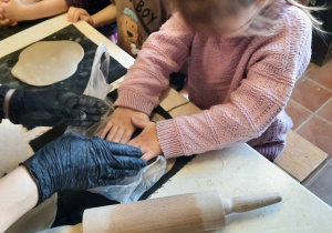 Dziewczynka za pomocą foremki wykrawa wzór serca w kawałku gliny.