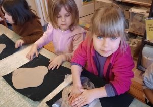 Dziewczynka za pomocą foremki wykrawa wzór serca w kawałku gliny.