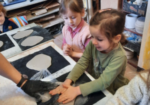 Dziewczynka za pomocą foremki wykrawa wzór serca w kawałku gliny.