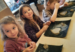 Trzy dziewczynki i chłopiec ozdabiają swoje serduszko małymi kuleczkami z gliny.