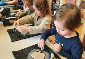 Trzy dziewczynki i chłopiec formują małe kuleczki z nadmiaru gliny.