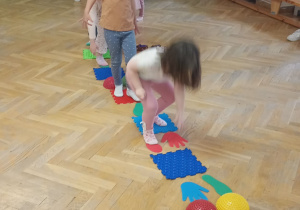 Dzieci stoją w pociągu, przechodzą po kolei po torze sensorycznym.