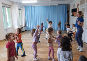 Dzieci podskakują machając rękoma nad głową.