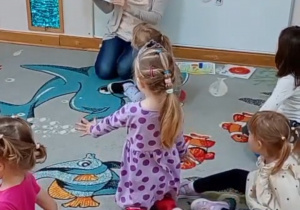 Nauczycielka czyta polecenie w książce pt. "The dot".