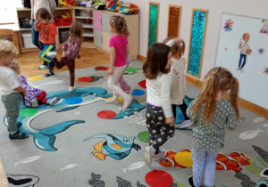 Dzieci stoją na jednej nodze obok krążka w kolorze żółtym.