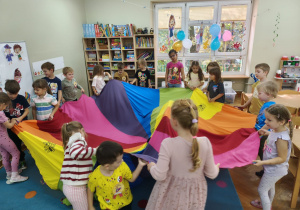 Starszaki trzymają chustę animacyjną, a te które stoją przy kolorze fioletowym zamieniają się miejscami przechodząc pod chustą.