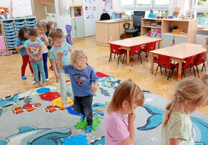 Maluchy przechodzą po ułożonym na dywanie torze sensorycznym.