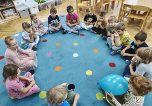 Starszaki siedzą w kole, jeden z chłopców trzyma w rękach balon.