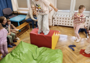 Dziewczynka skacze ze schodów na poduszkę.