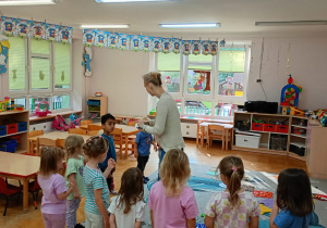 Nauczycielka rozdaje maluchom odznaki na Dzień Przedszkolaka.