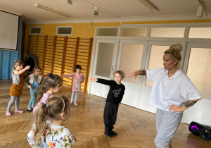 Dzieci tańczą razem z instruktorką. Wykonują zwrot w lewą stronę.