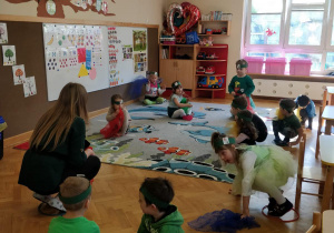 Zabawy podczas pierwszego dnia wiosny. Dzieci na umówiony znak nauczycielki wchodzą do obręczy na dywanie.