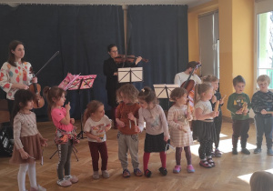 Dzieci grają na instrumentach razem z muzykami podczas koncertu filharmonii.
