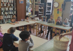 Pani pokazuje dzieciom jak będą wykonywać prace podczas warsztatów ceramicznych.