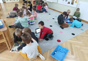 Dzieci siedzą w małych grupkach i próbują ułożyć robota z klocków Lego na zajęciach z robotyki.