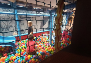 Dzieci bawią się w basenie z dużą ilością kolorowych kulek.
