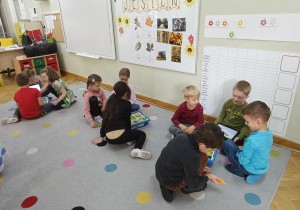 Dzieci siedzą na dywanie i starają się zbudować własnego robota z klocków Lego na zajęciach z robotyki.